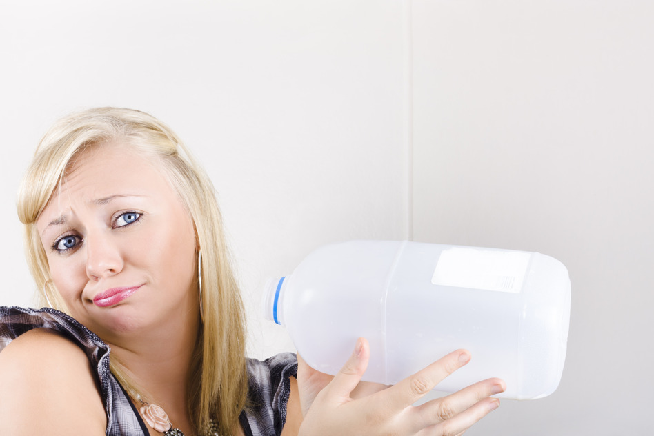 Unhappy Young Woman Holding Empty Milk Bottle